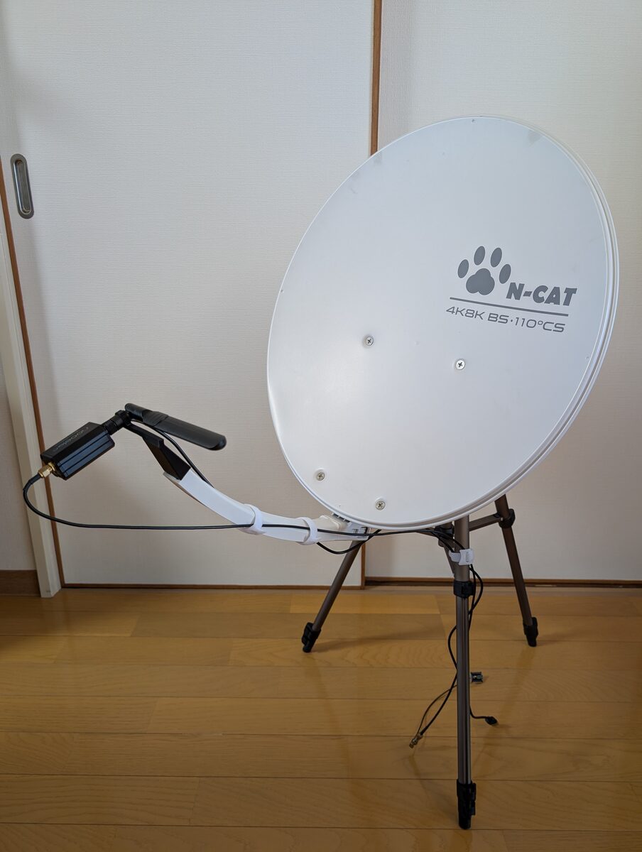 The 45 cm offset dish on a camera tripod, in its normal orientation with the feed arm below the dish. At the end of the arm, a home-made mount holds the rod antenna across the focal point, with the Nooelec LaNA attached directly to the antenna.